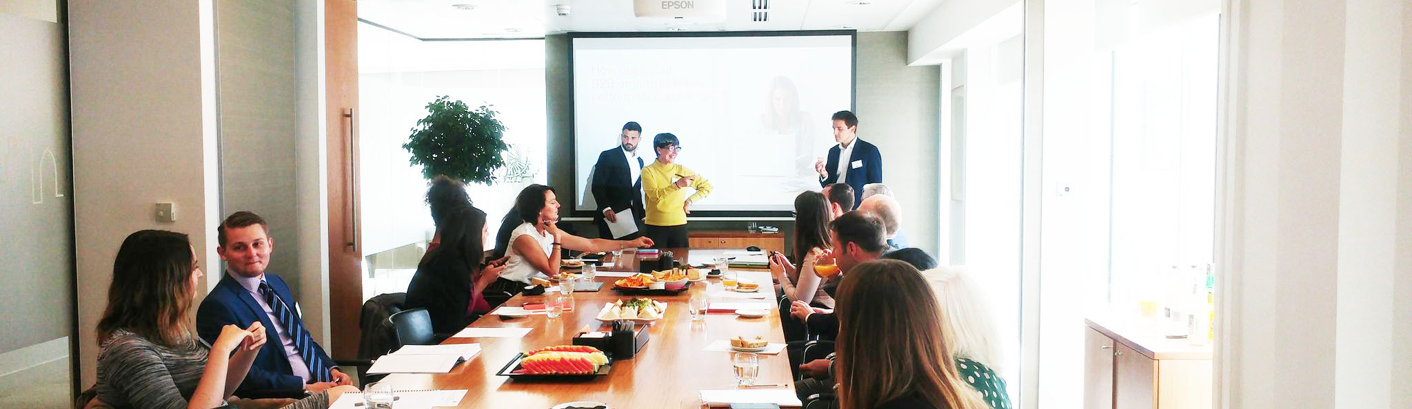 A Concep meeting, with colleagues seated around a long table and presenters by a screen