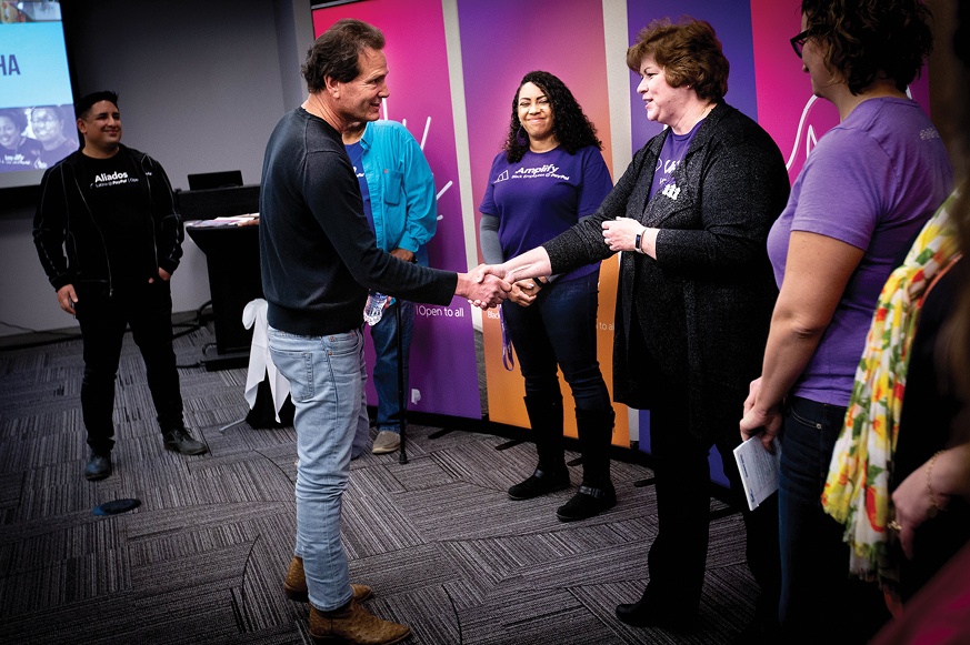 Dan Schulman shakes hands with a PayPal employee as colleagues look on in Omaha