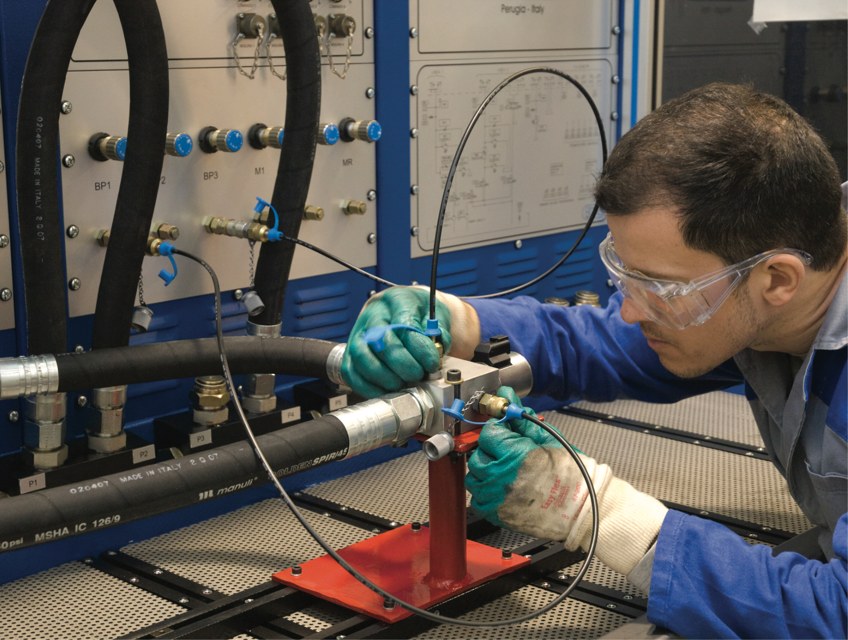 Dana employee wearing safety glasses and gloves while working on a component connected to a test rig