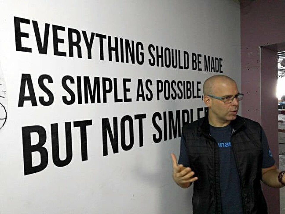 Dani Golan talking in the Kaminario office beside a wall bearing a motto about simplicity