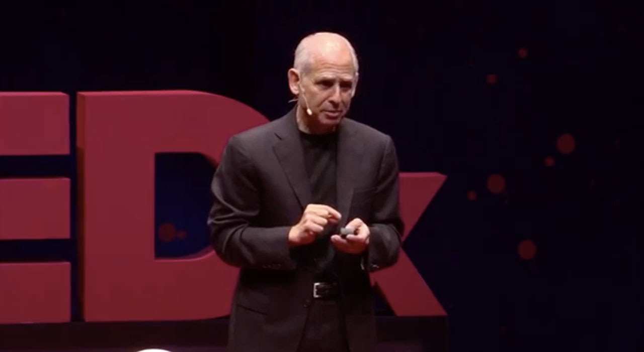 Daniel Amen holding a presentation remote on the TEDxOrangeCoast stage