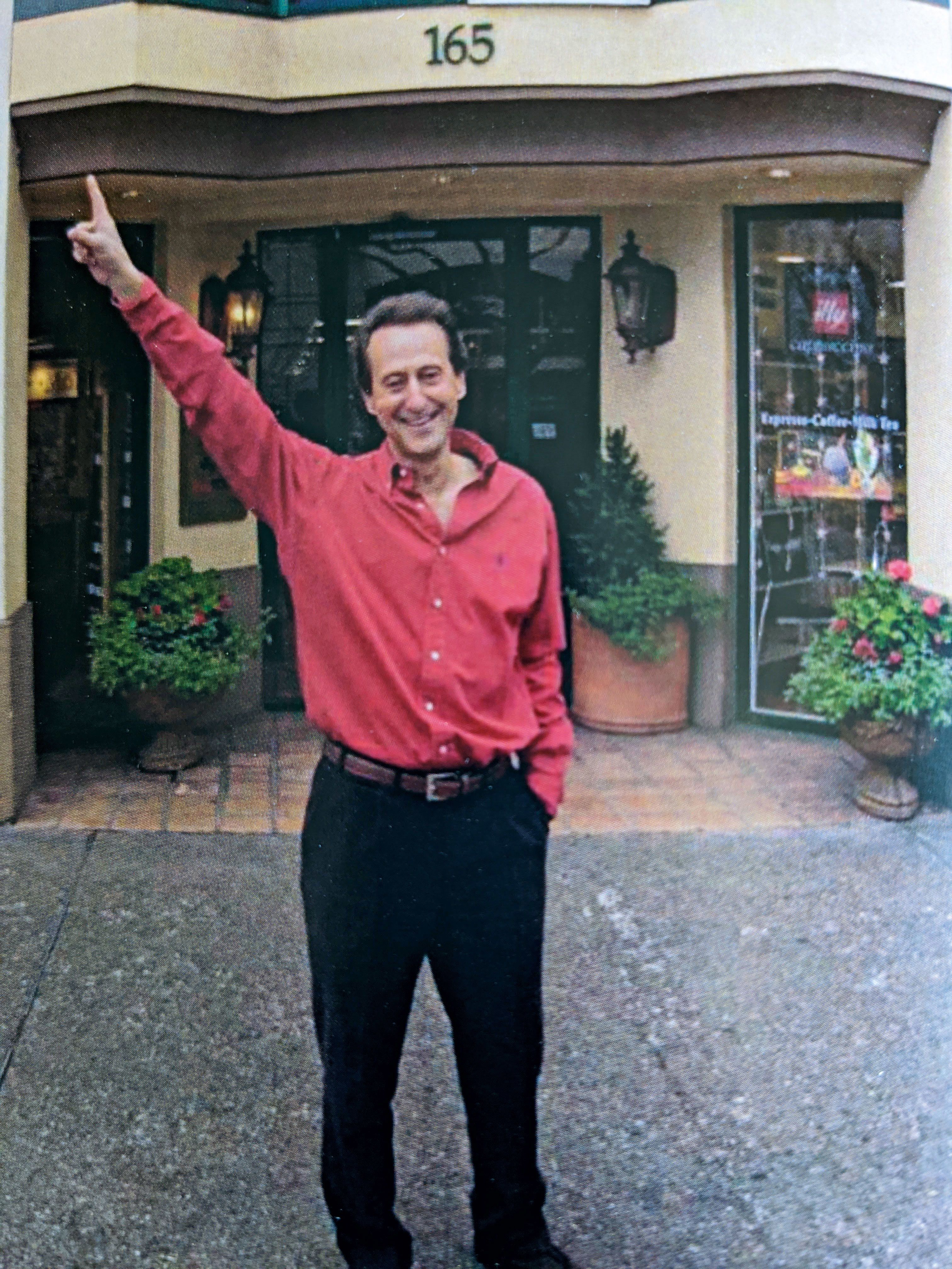 Daniel Borel in a red shirt pointing to the number above 165 University Avenue in Palo Alto