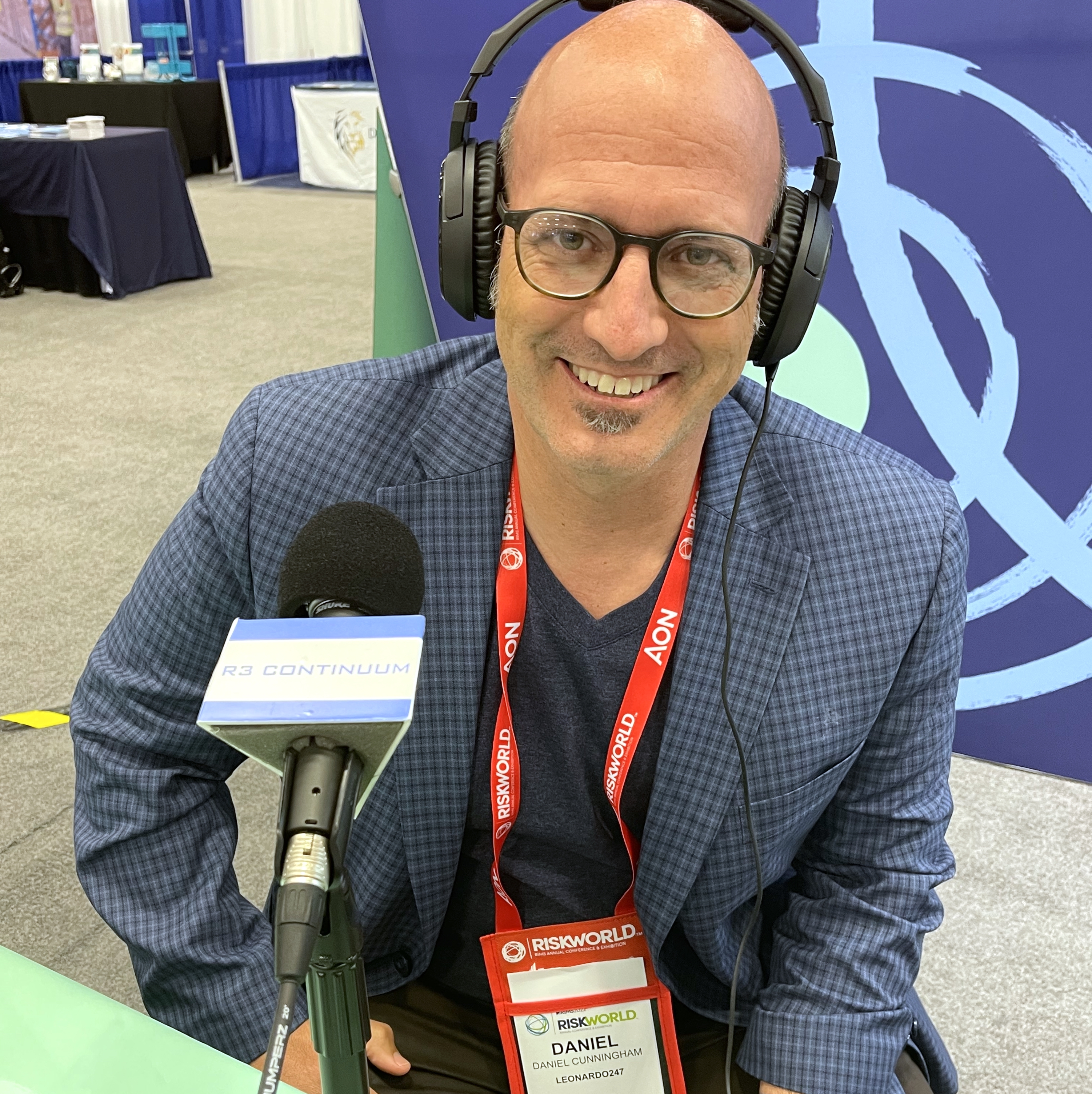 Daniel Cunningham wearing headphones and speaking into a microphone at RISKWORLD 2022