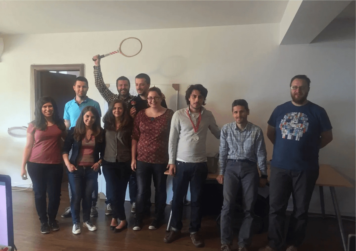 Daniel Dines raises a tennis racket among members of the early UiPath team