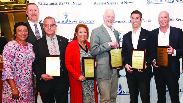 Seven awards attendees holding plaques; Daniel Etra stands second from right beside Eran Rosenthal at far right.