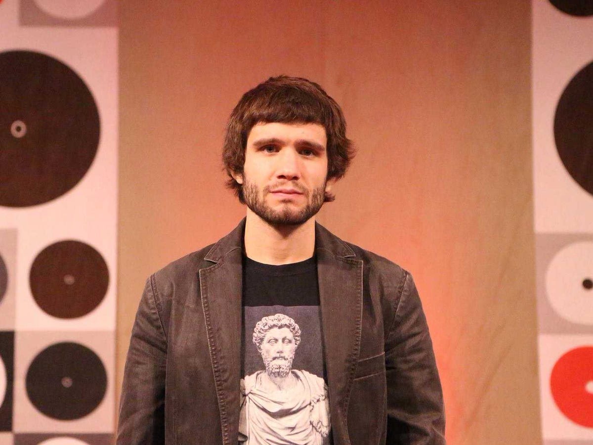Daniel Faggella at a speaking event, wearing a blazer and a shirt depicting a classical bust