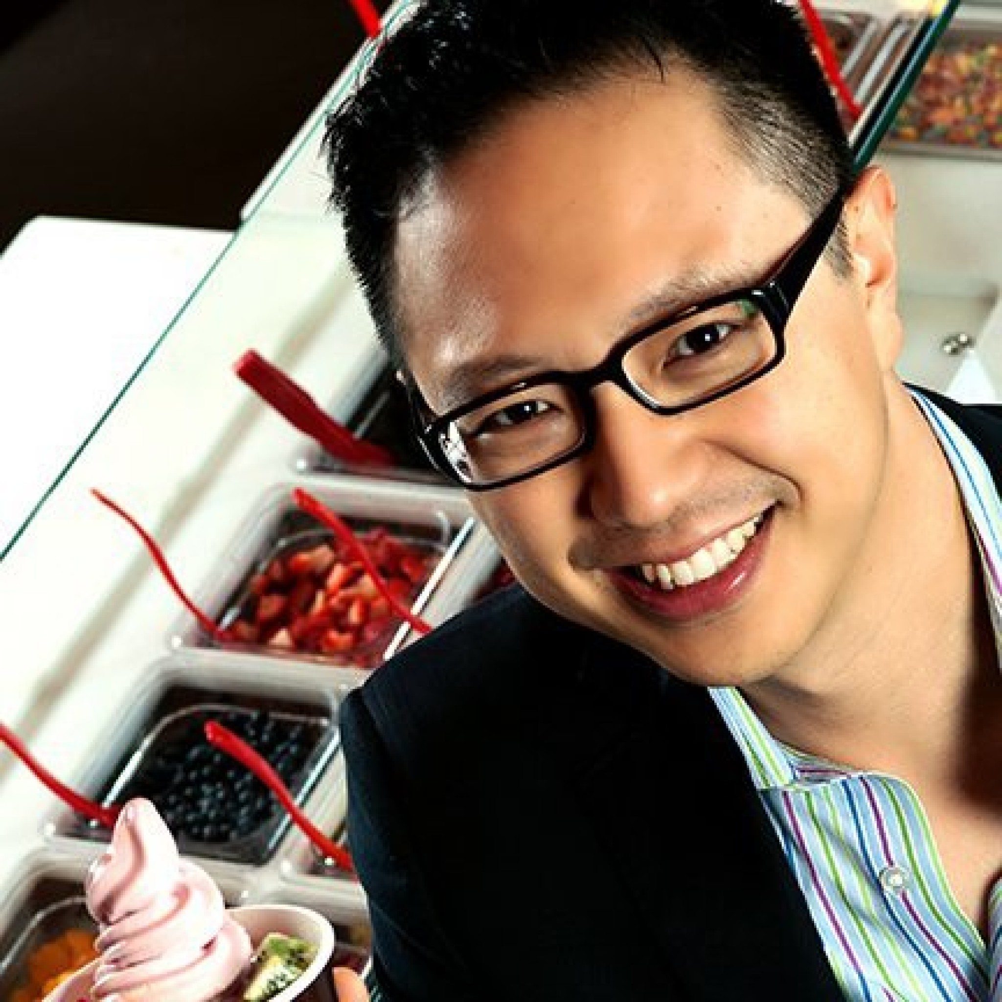 Daniel J. Kim smiling beside a frozen-yogurt toppings counter