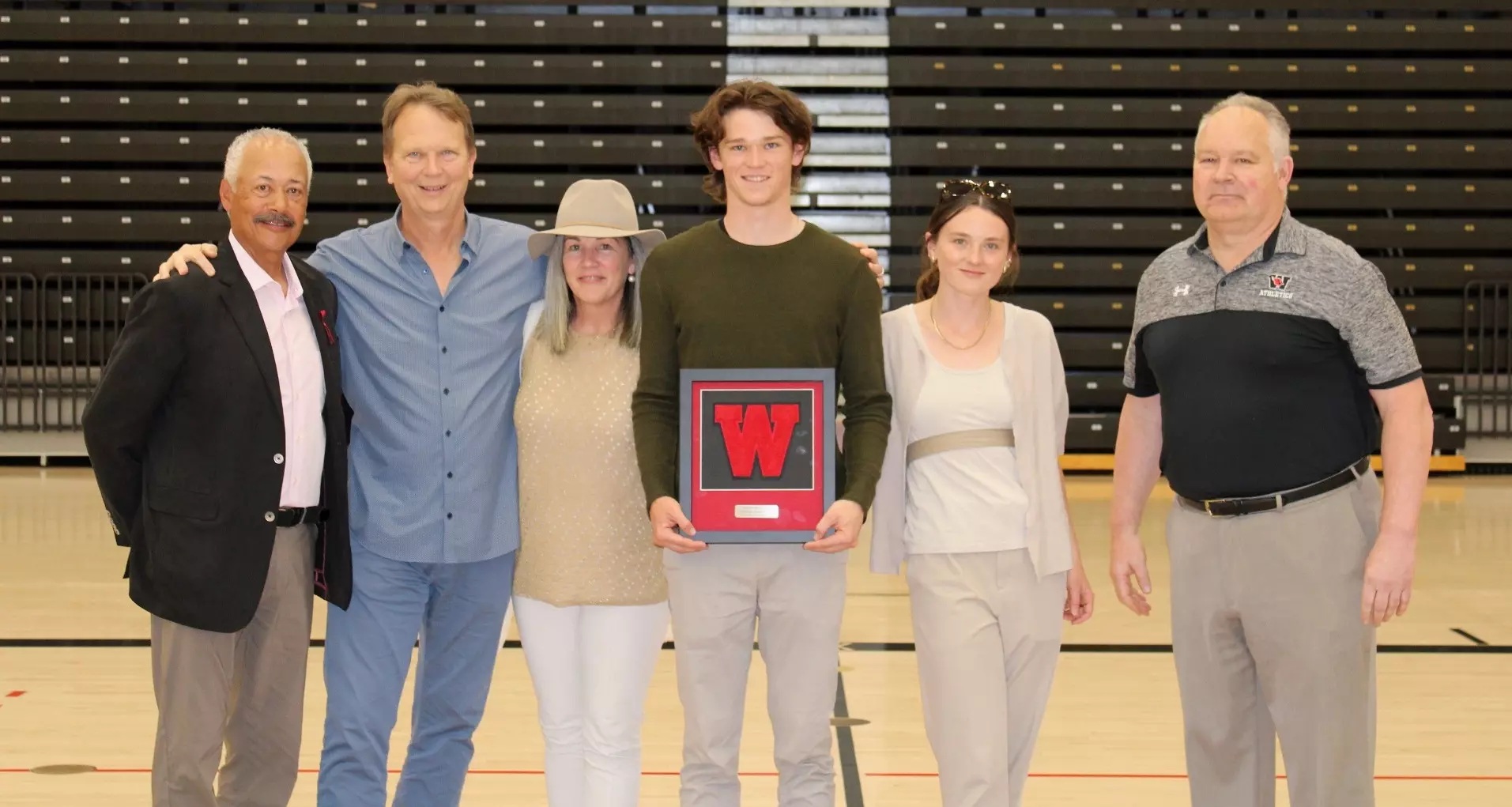 Daniel Kraft holding Wesleyan's Cardinal Award alongside a group at the athletics ceremony