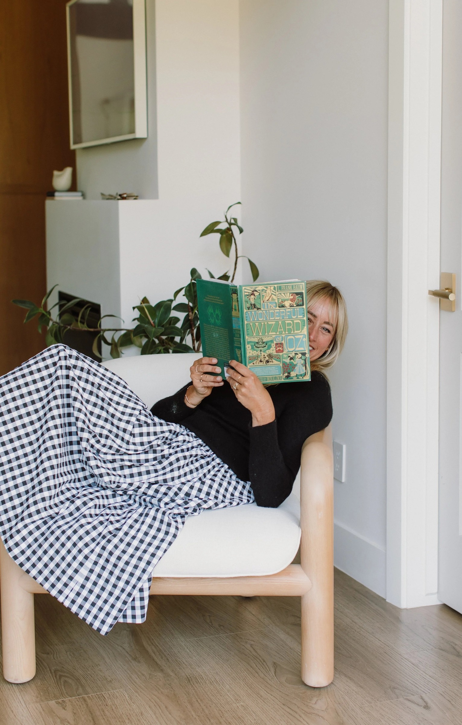 Danielle Finck sitting in a chair with a copy of The Wonderful Wizard of Oz raised in front of her