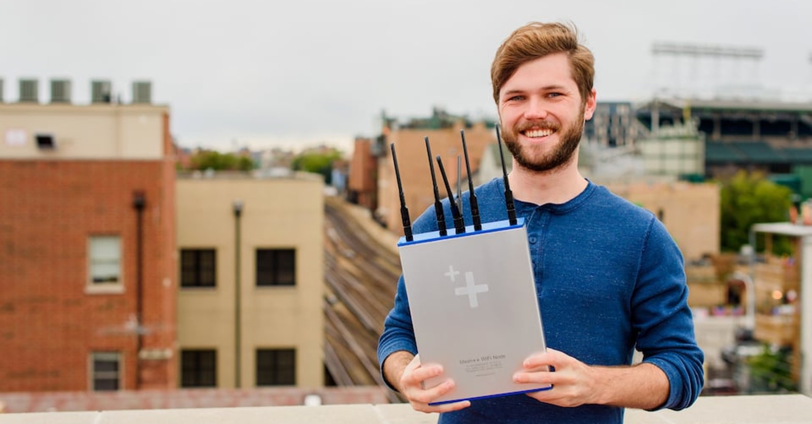 Danny Gardner outdoors in Chicago holding an early Mesh++ wireless router with several antennas