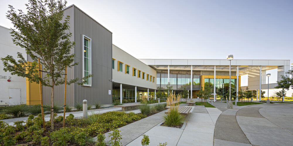 Madera Community College Academic Village Two with gray walls, yellow accents and a landscaped walkway