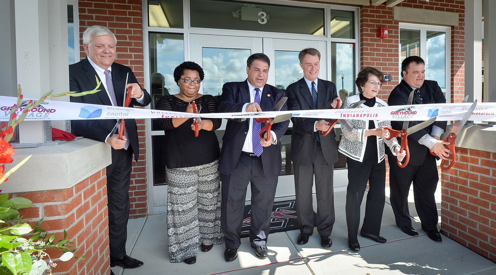 Gene Zink, at left, cutting the Greyhound Village ribbon alongside student Erin Jackson and university and city leaders