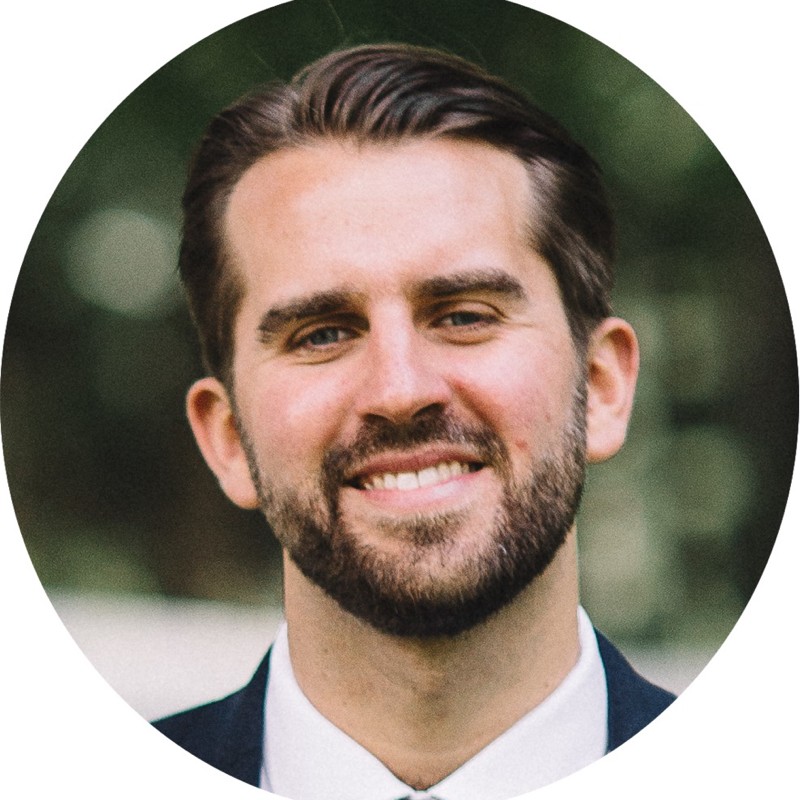An archival portrait of Darren Bassman smiling in a suit