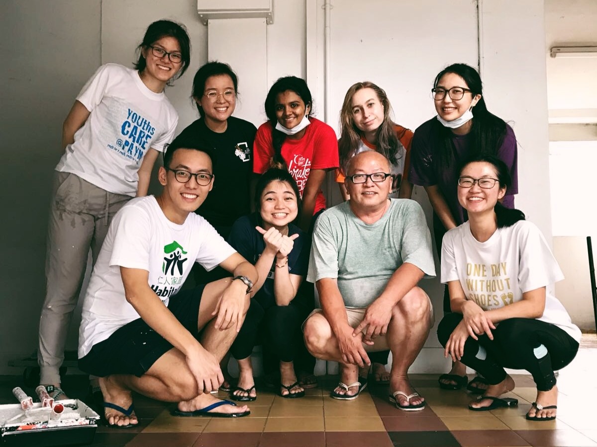 A group of Habitat Singapore volunteers and a homeowner gathered indoors