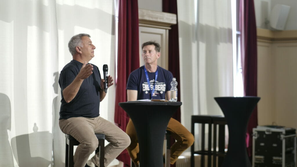 Darryl Rawlings, holding a microphone, speaks beside investor Rob Vinall in Engelberg.