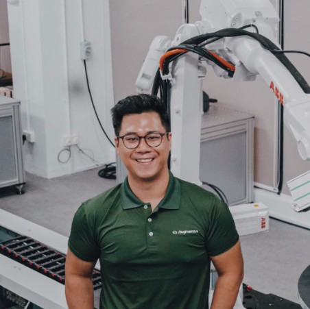 Daryl Lim, co-founder and CEO of Augmentus, standing in front of an ABB industrial robot arm