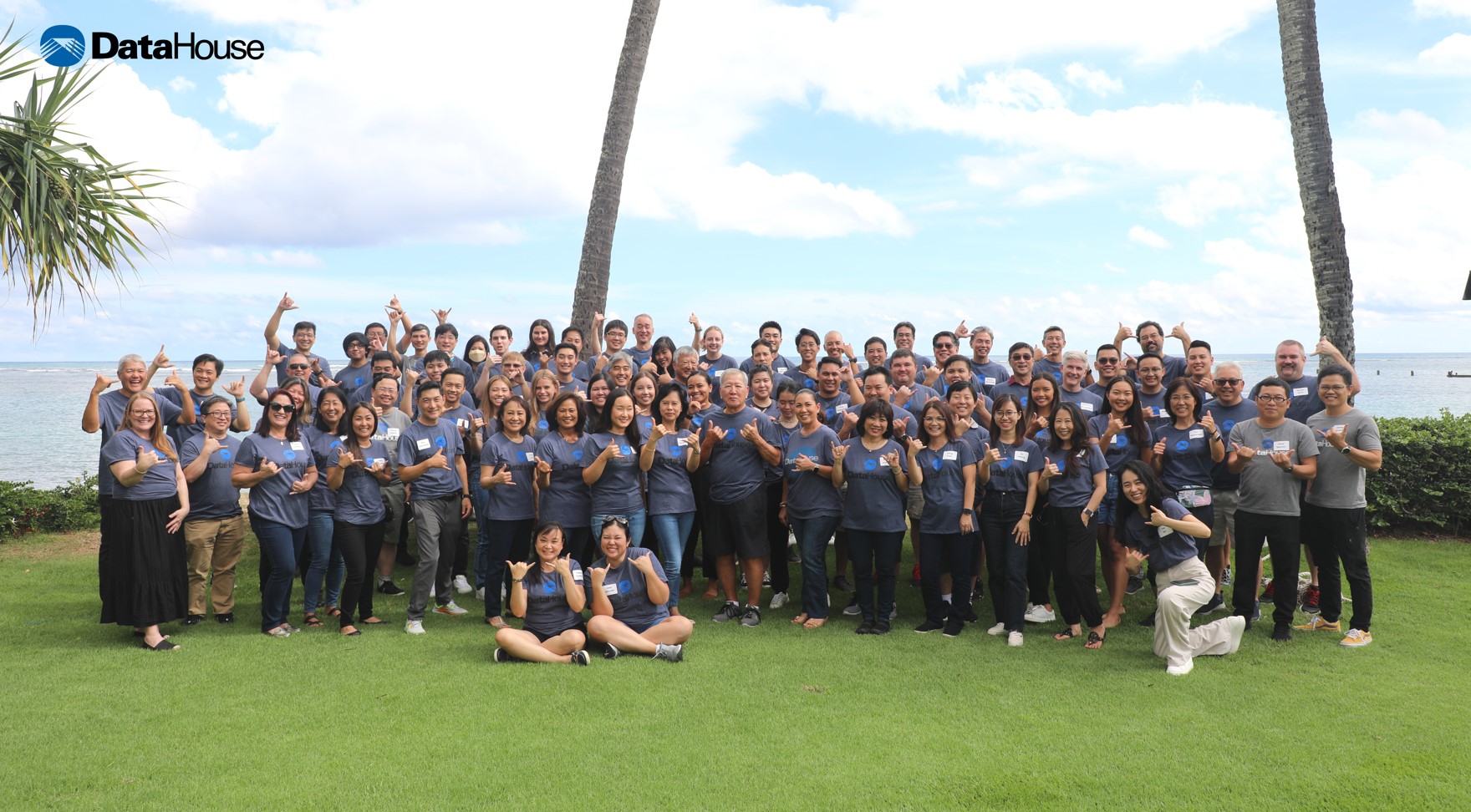 DataHouse colleagues gathered on a lawn beside the ocean