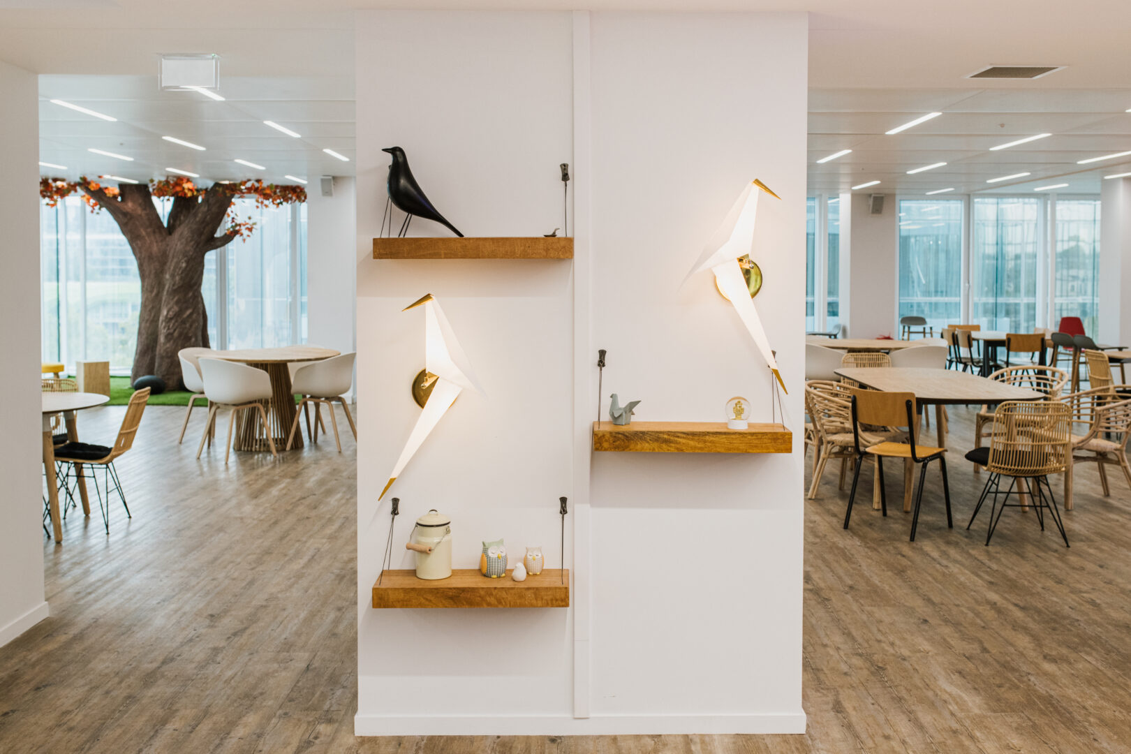 A bright Dataiku office with origami bird lights, mismatched chairs and an indoor tree
