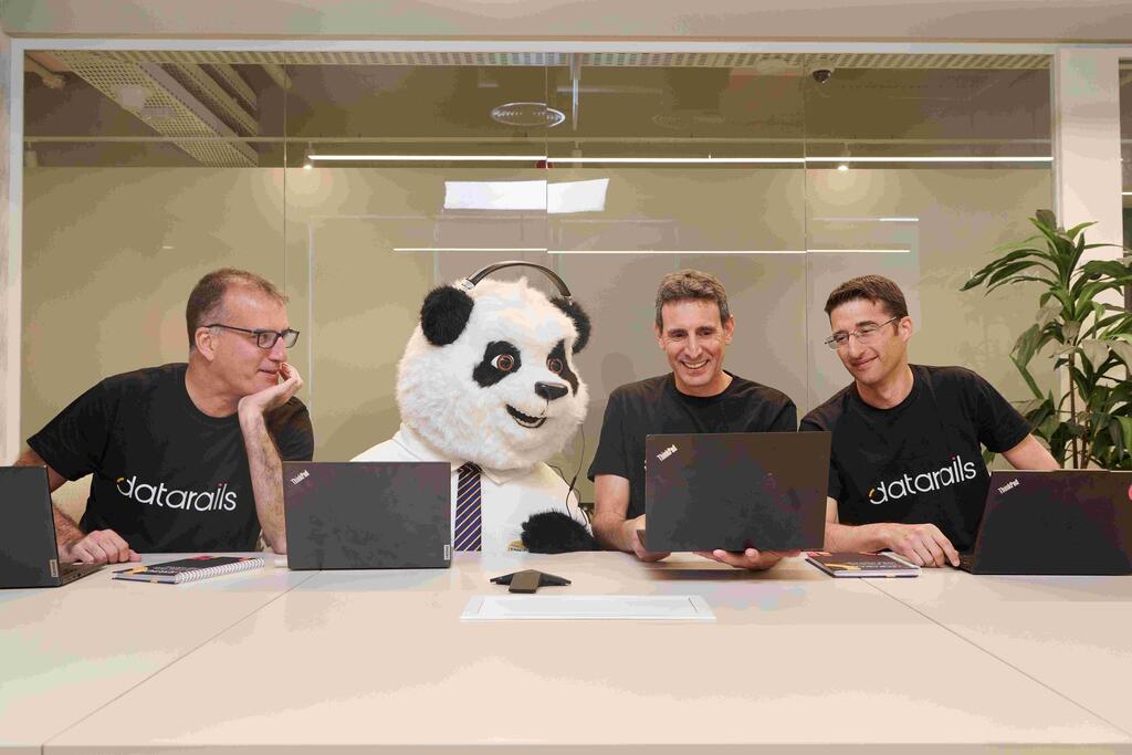 Datarails co-founders at a conference table with laptops and a panda mascot in a tie