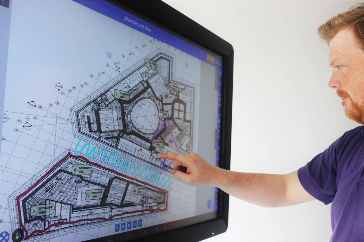 A construction manager points to DataTouch work zones on a large interactive site plan