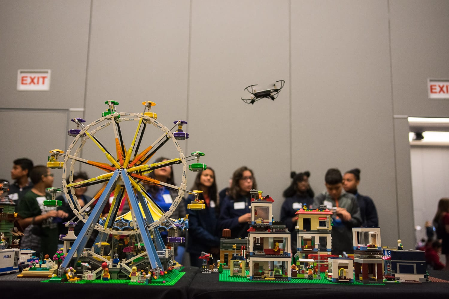 A small drone flies above a detailed model city while students watch at UCF GIS Day 2019.
