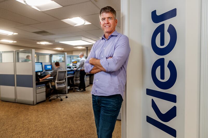 Dave Monahan standing beside the Kleer sign in the company’s open-plan Wayne office in 2018.