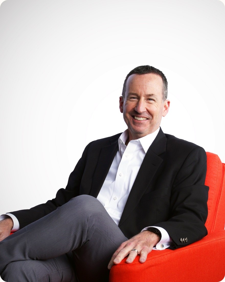 Dave Smith seated in an orange chair, wearing a dark jacket and white shirt