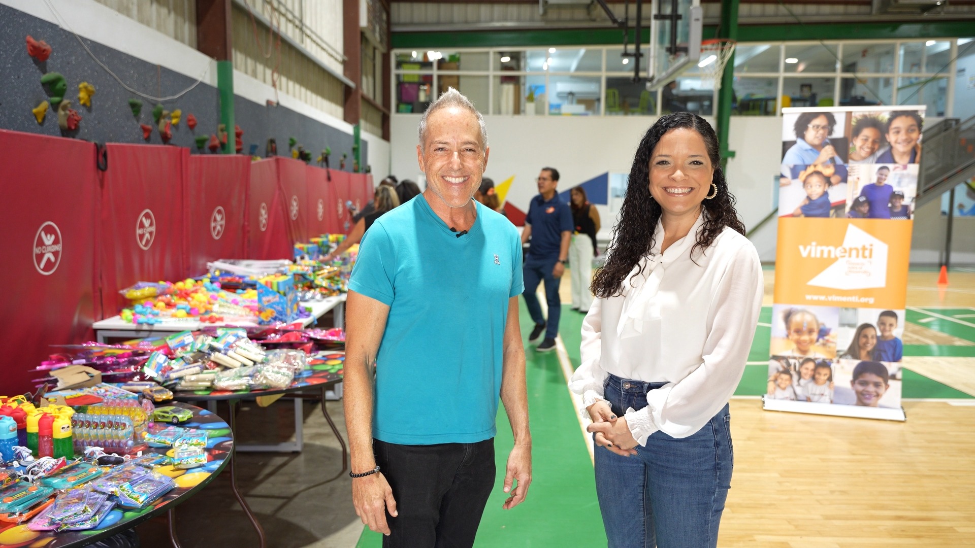 Daven Michaels beside tables of donated toys at a Vimenti community event.