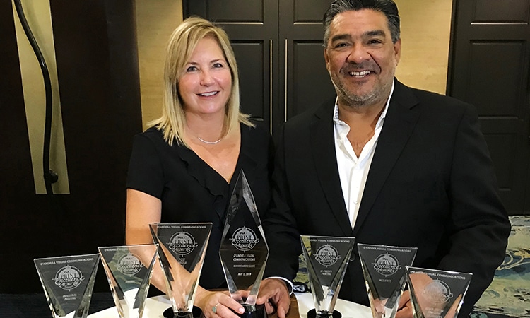 Denise Okata and David D’Andrea standing behind DVC’s print awards
