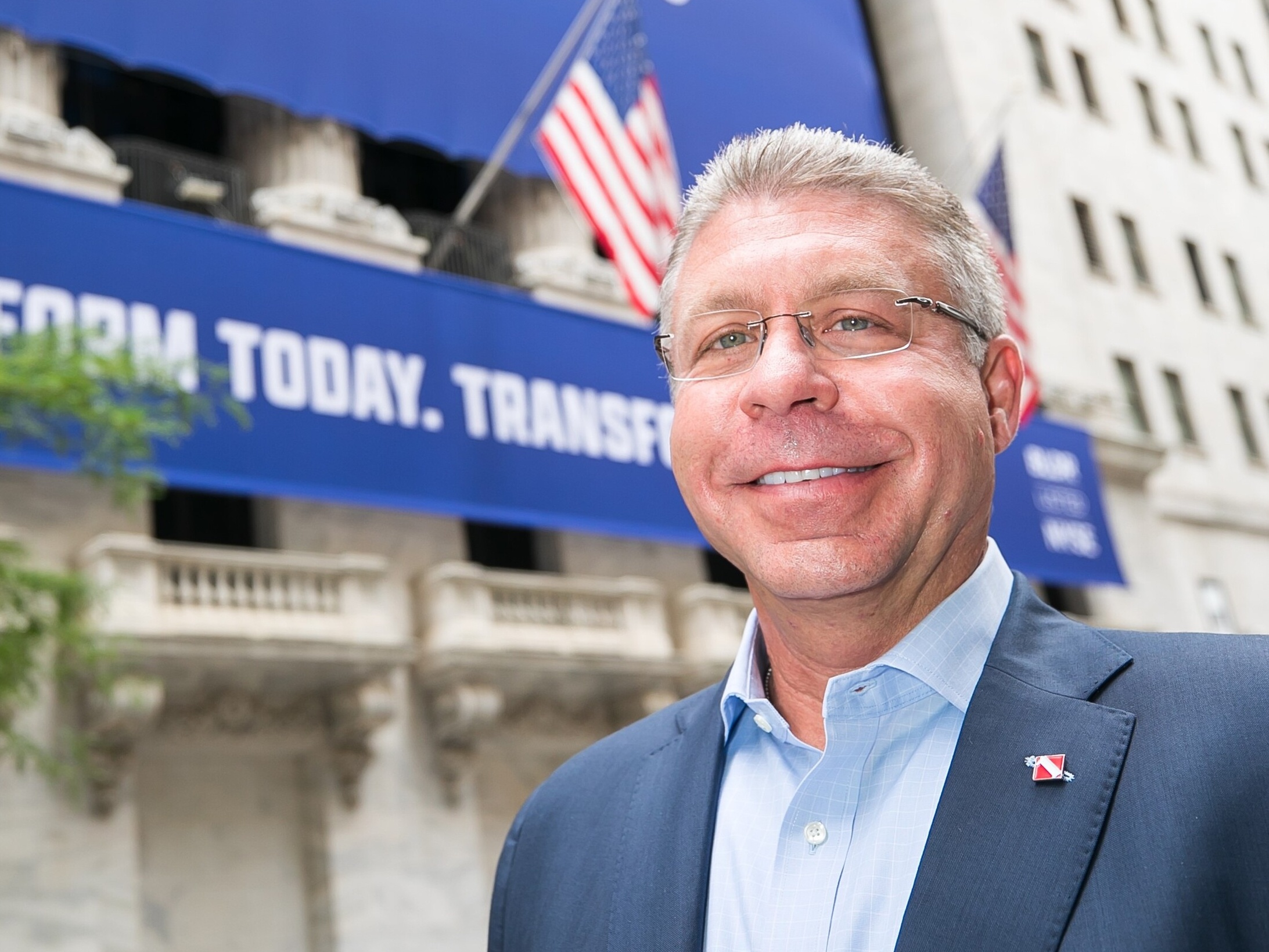 Dave Flitman outside the New York Stock Exchange, with a Builders FirstSource banner behind him