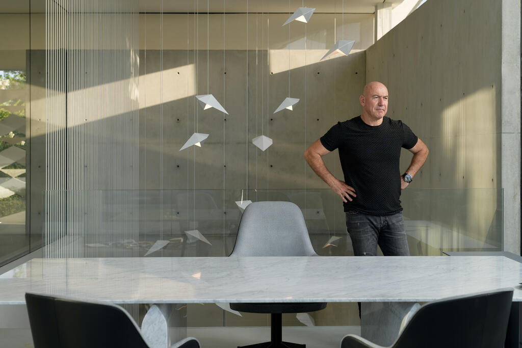 David Gershon standing beside a table and hanging sculptures in his home