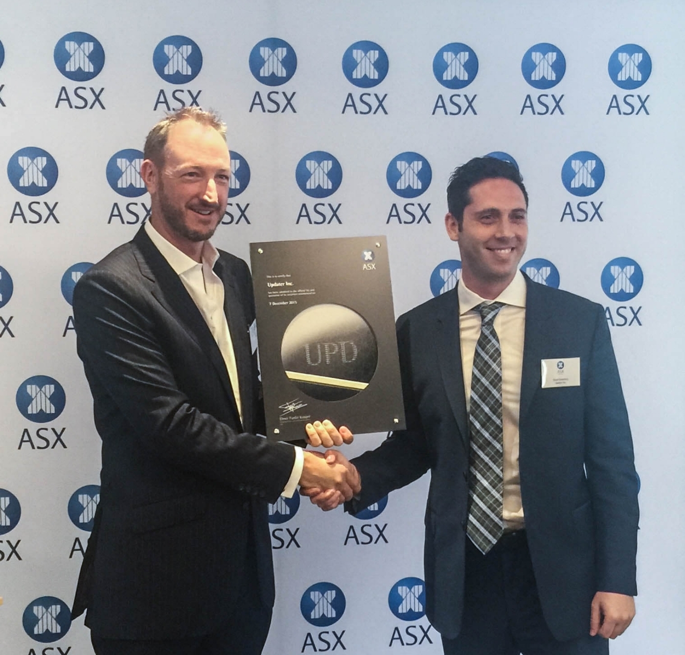 David Greenberg, right, shaking hands while holding Updater’s ASX listing plaque