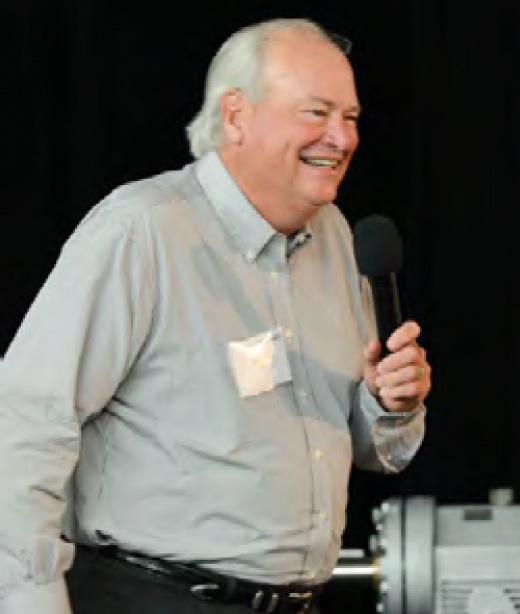 David Little smiling while holding a microphone, in a photograph published by DXP