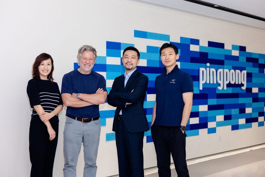 David Messenger standing with PingPong Payments colleagues in front of the company logo