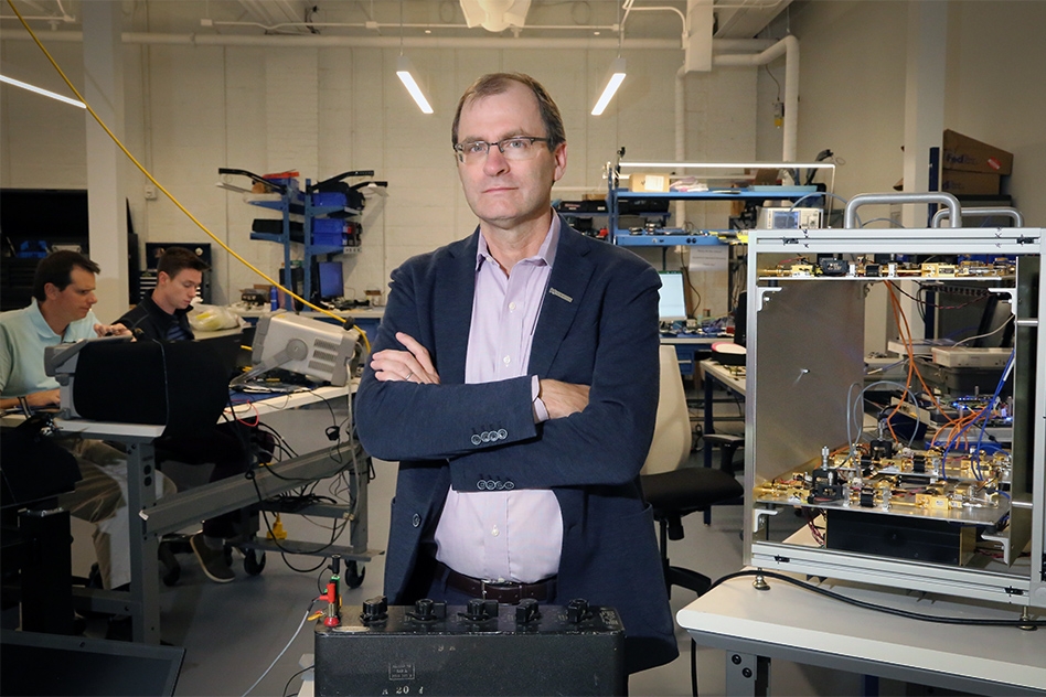 David Mindell standing among electronics and workbenches at Humatics’ Waltham headquarters