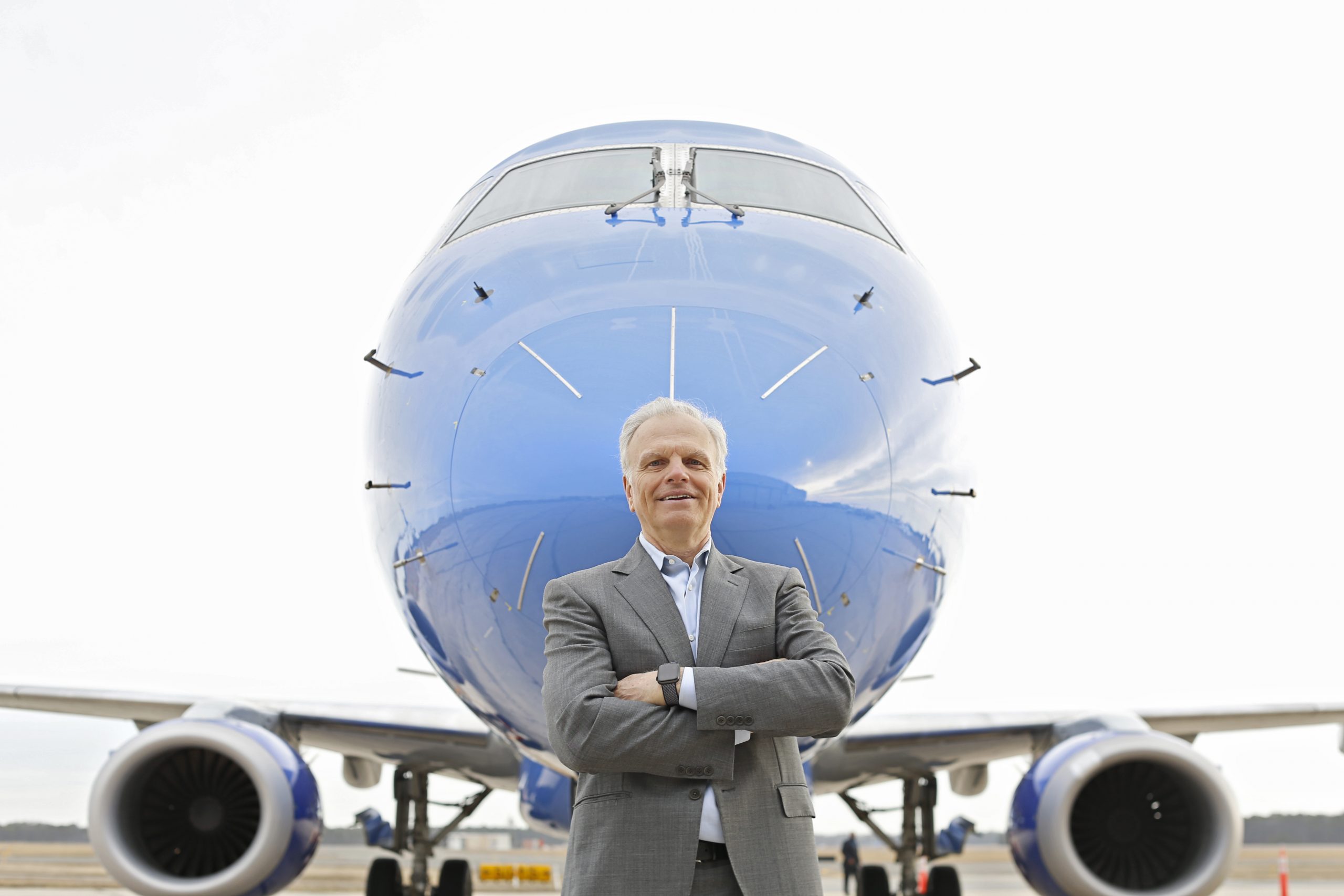 David Neeleman standing in front of a blue Breeze Airways Embraer aircraft