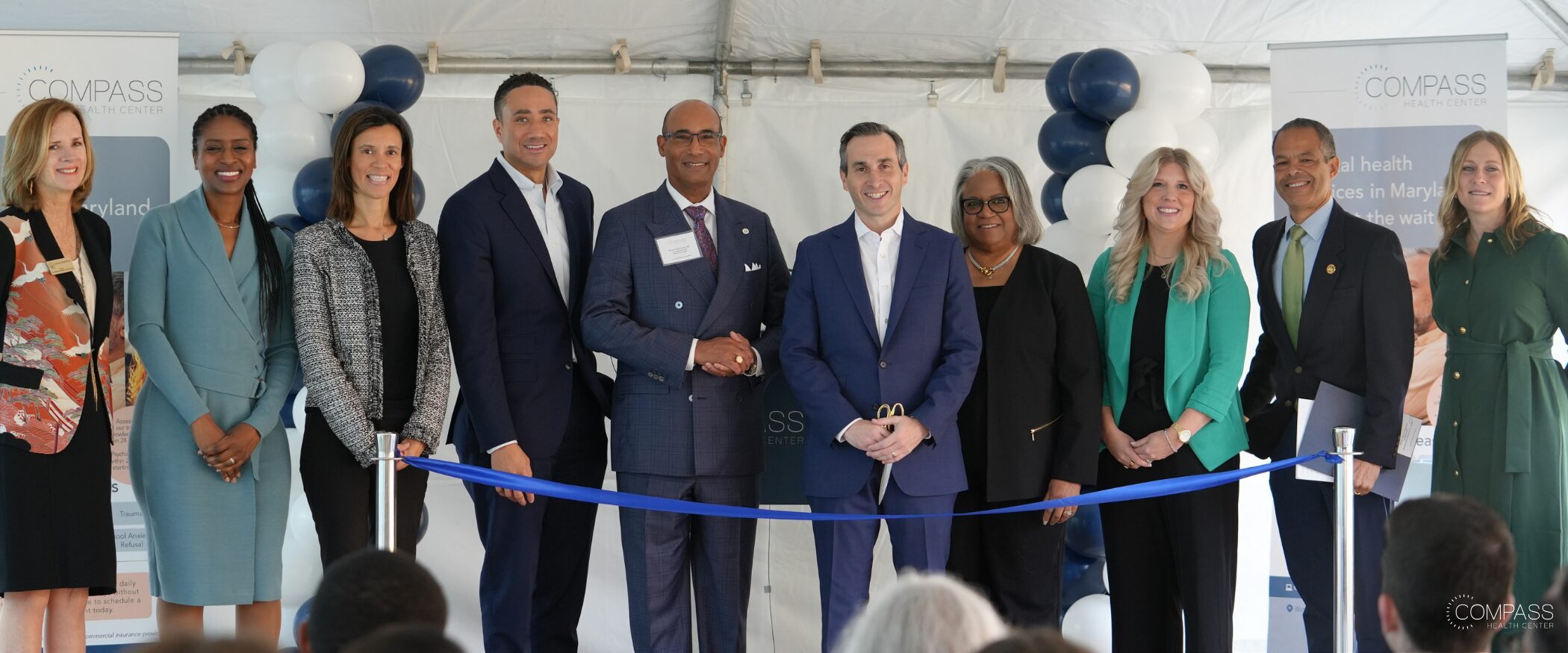 David Schreiber stands sixth from left with colleagues and community representatives behind a blue ribbon at the Maryland opening.