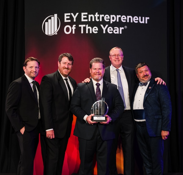 David Sisk, center holding an award, with four colleagues at the 2025 EY Entrepreneur Of The Year celebration