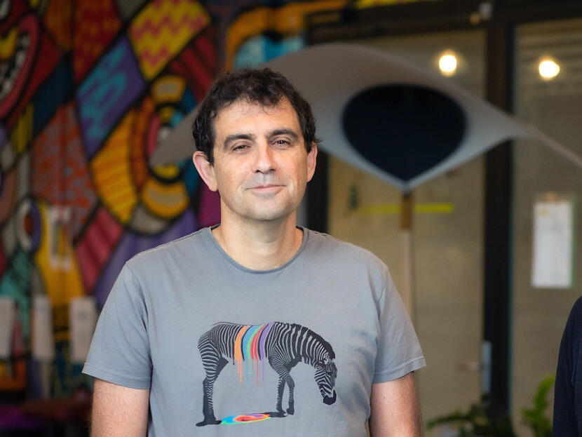 David Sosna in a gray zebra-print T-shirt, standing in an office with a colorful mural