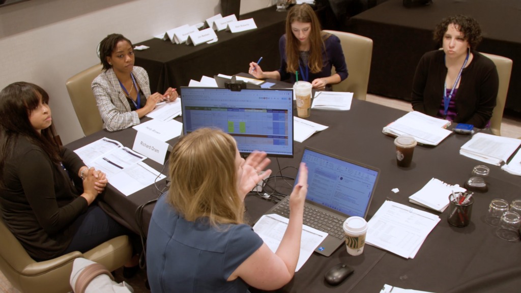 A Davis Management Group team works around a conference table with laptops, schedules and name cards