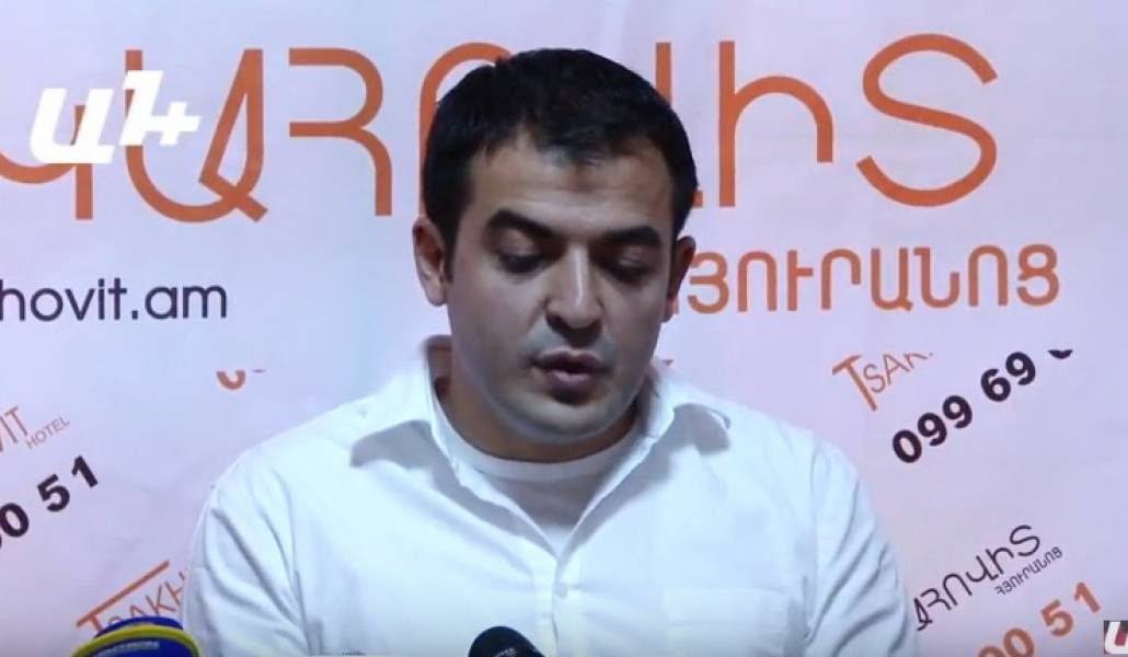 Davit Harutyunyan, wearing a white shirt, speaking into microphones at a press briefing
