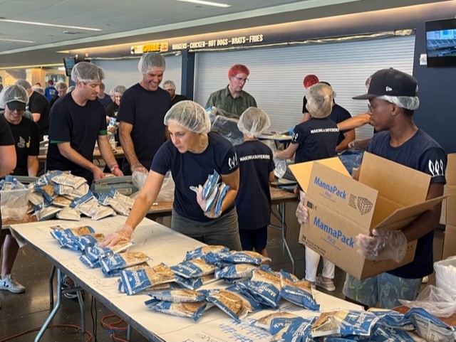 Dawn Owens and colleagues wearing hairnets and gloves while packing meals at a volunteer event