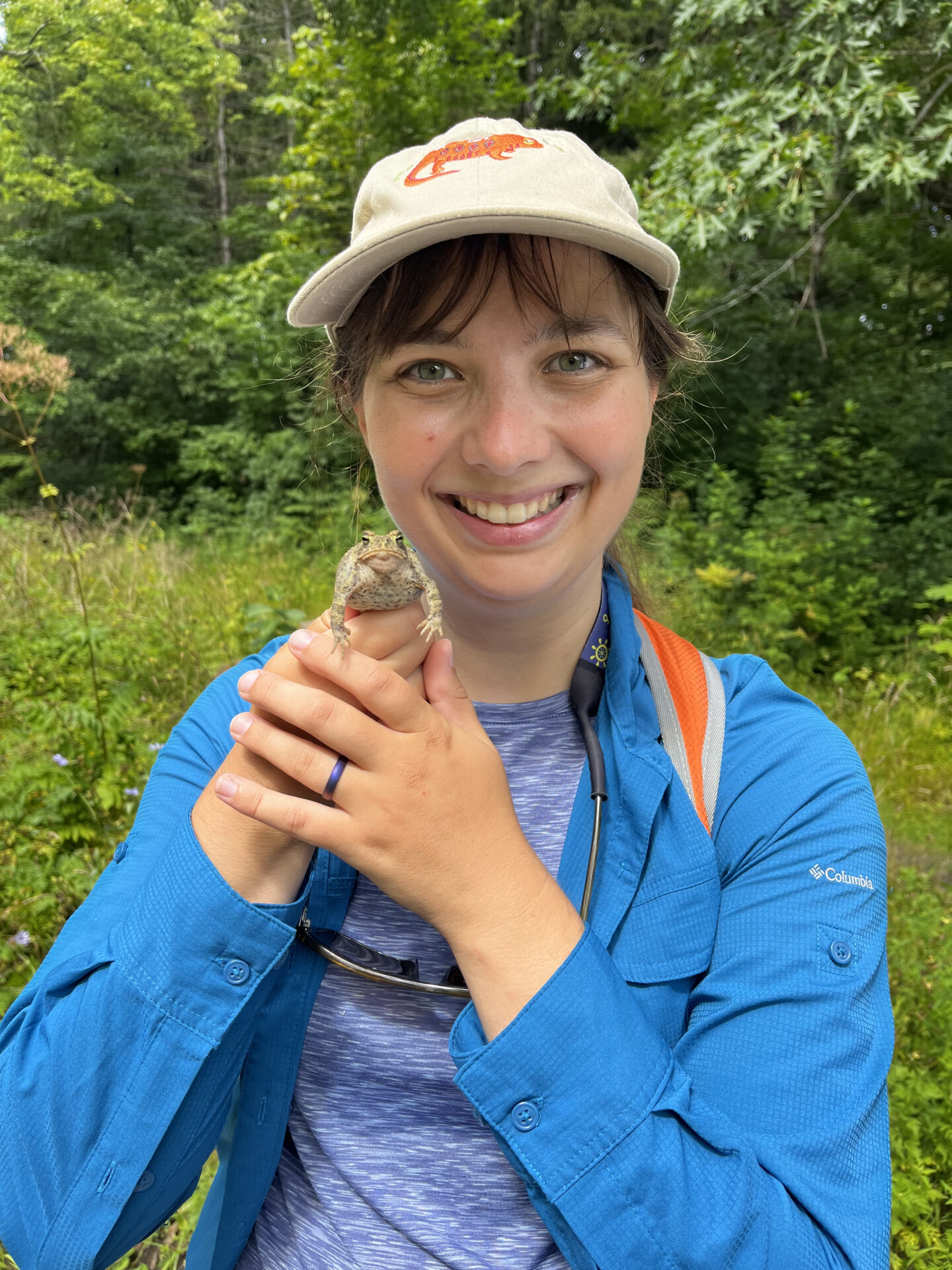 A Dawson College biology researcher holds a frog during fieldwork