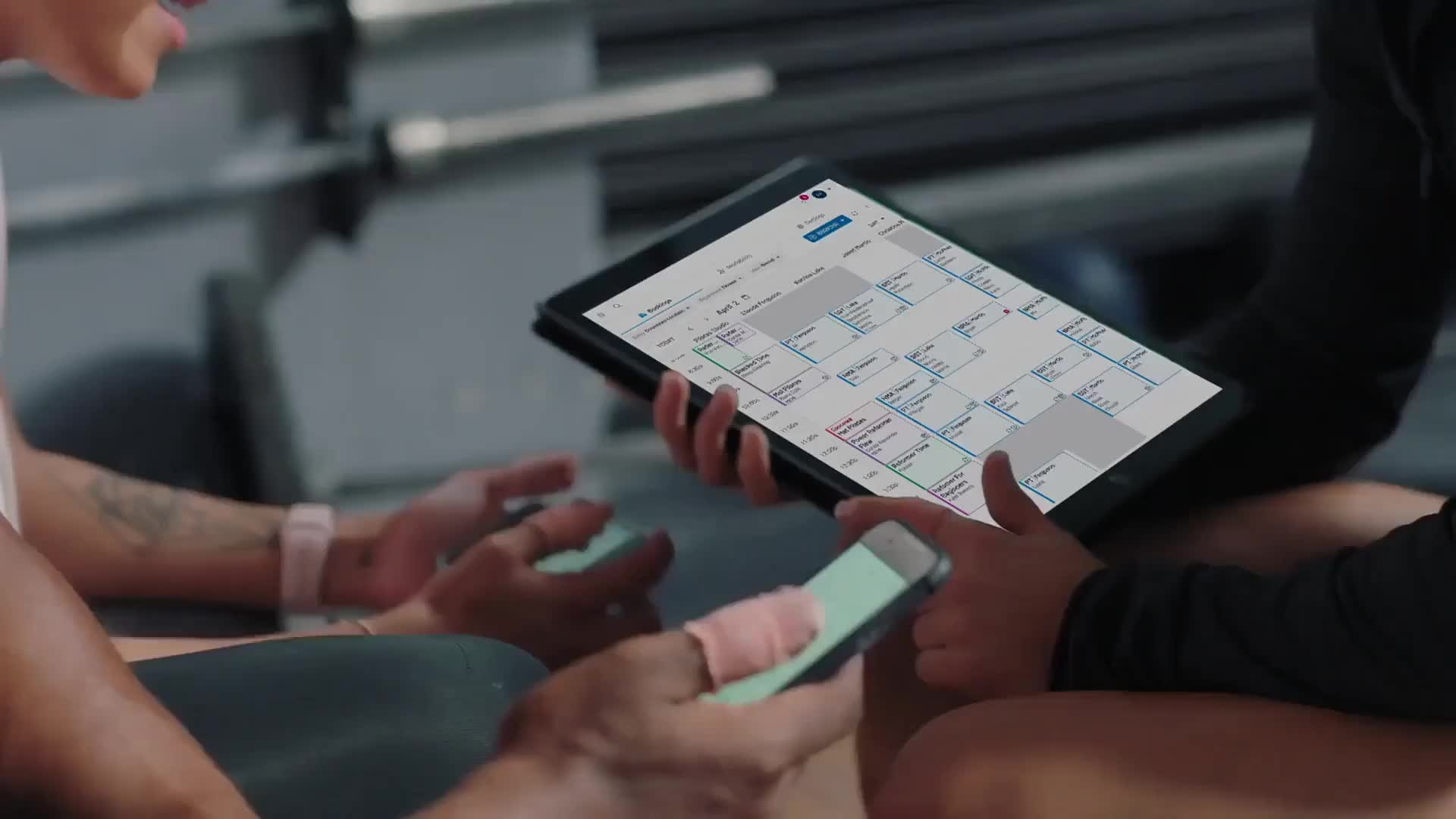 Club Automation promotional photograph showing a scheduling calendar on a tablet