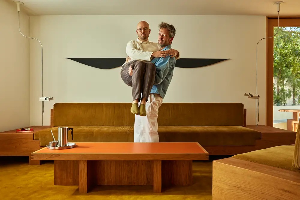 Day Job cofounders Spencer Madsen and Rion Harmon pose playfully in a warm wood-furnished interior