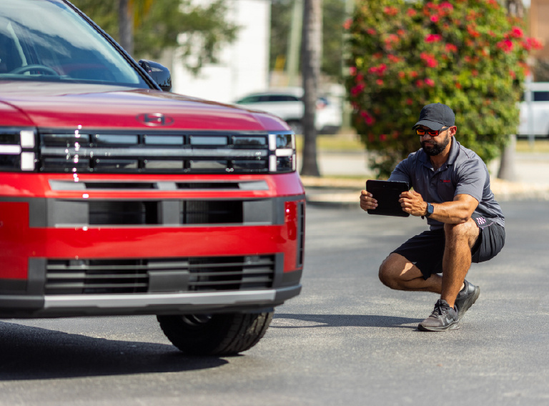 A Dealer Specialties photographer crouches with a tablet beside a red pickup truck
