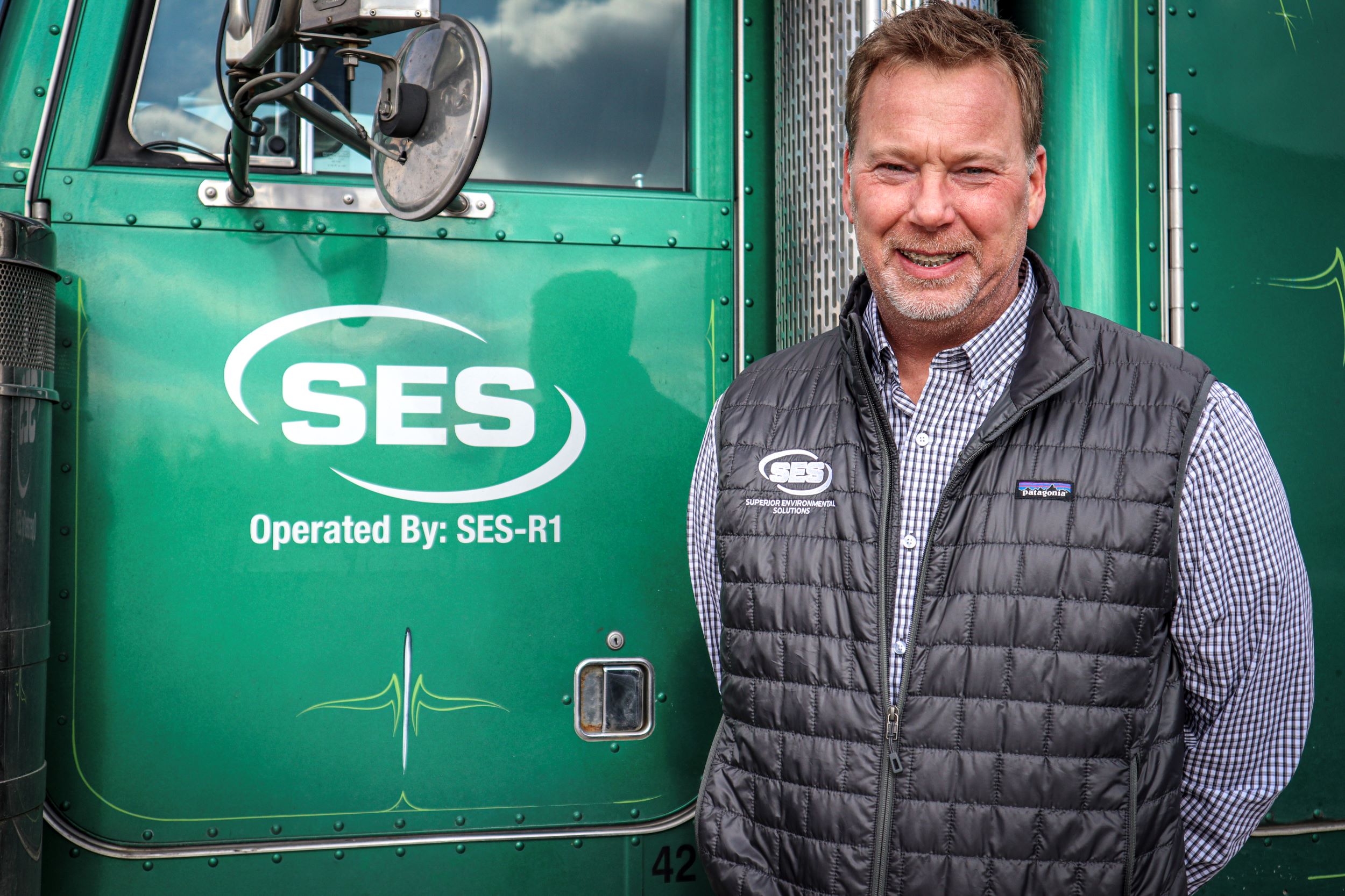 An SES-branded green truck beside an operator