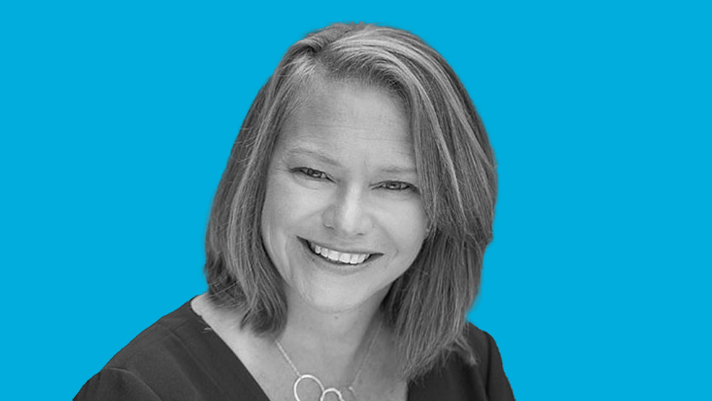 Deb Wolf smiling in an editorial portrait against a bright blue background