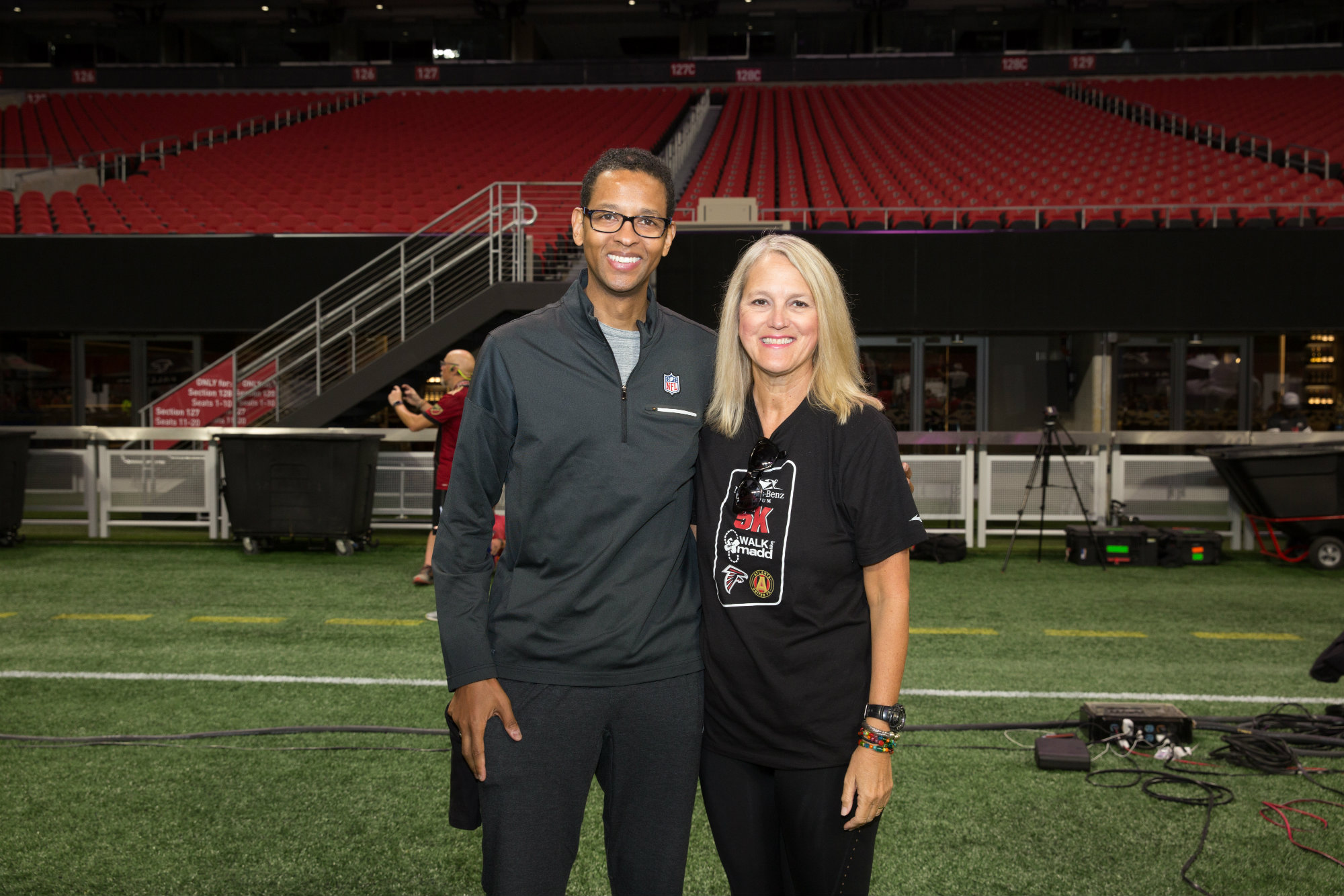 NFL executive Adolpho Birch and Debbie Weir standing on the field at Mercedes-Benz Stadium during a 2017 Walk Like MADD event