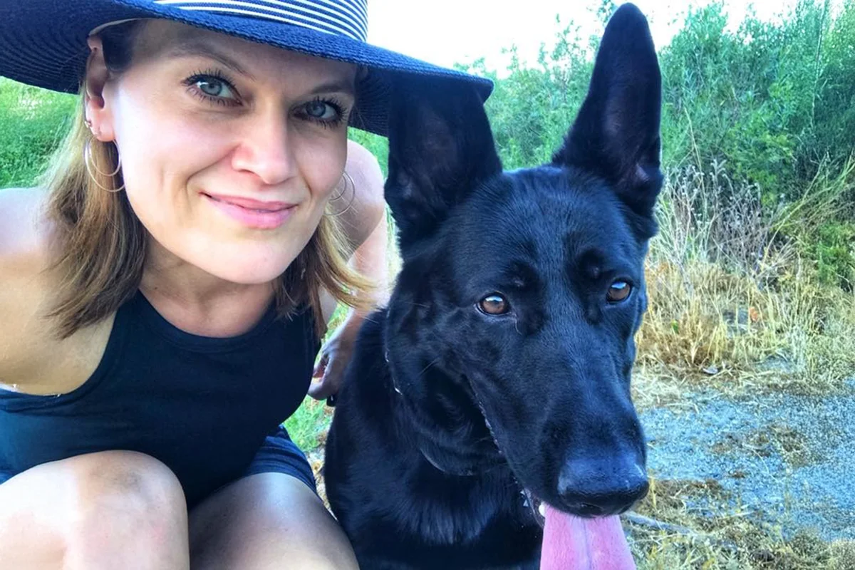 Debi Hammond outdoors in a sunhat beside a black dog